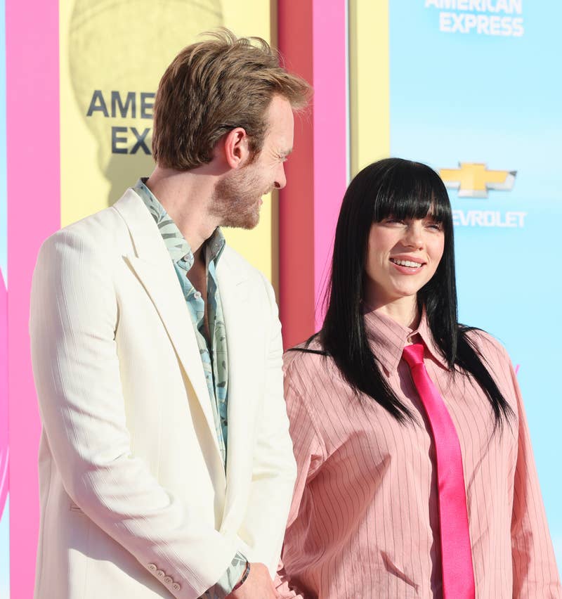 Close-up of Billie, with long, dark hair, and Finneas smiling at a media event
