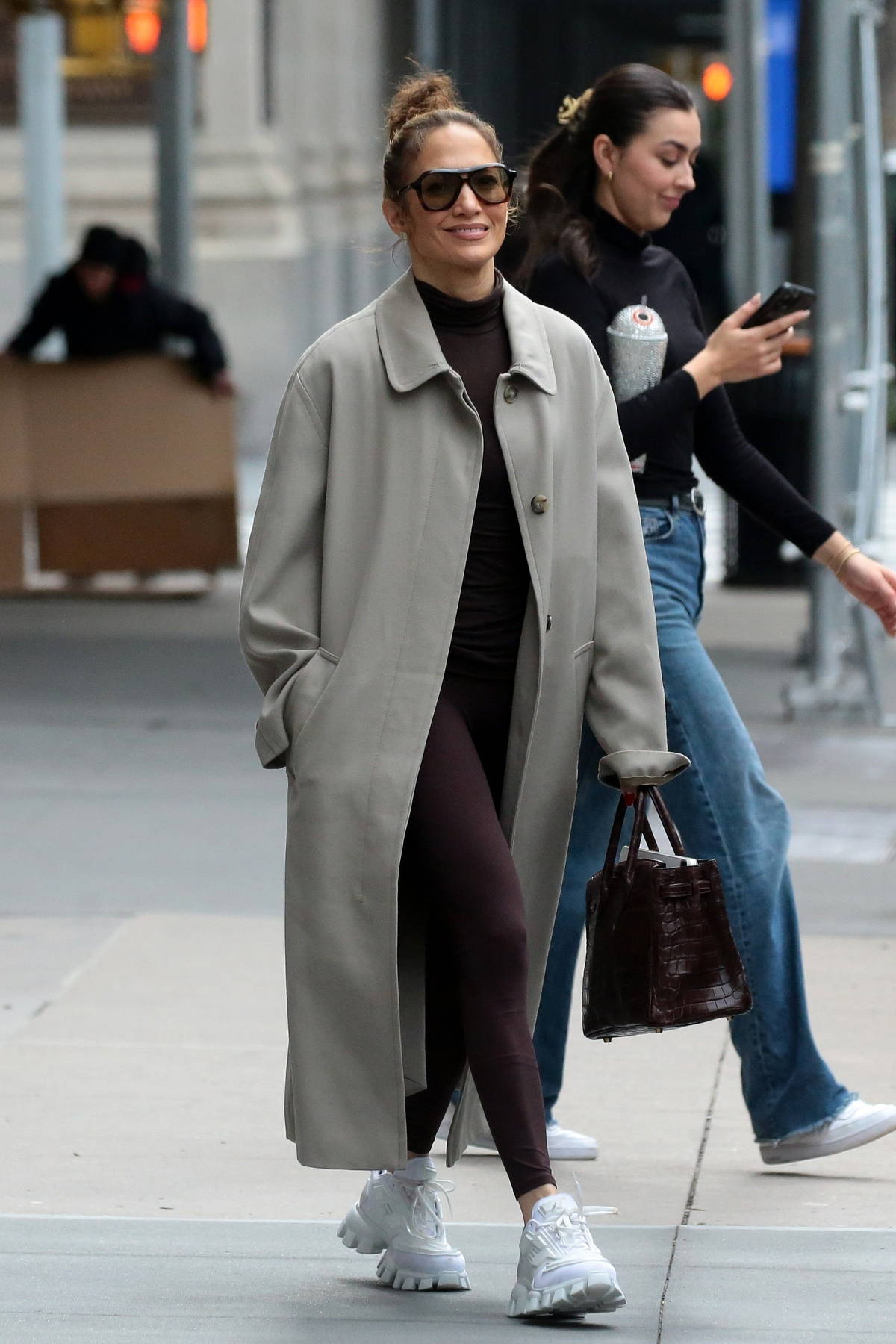 Jennifer Lopez sports brown top with matching leggings underneath a grey overcoat while heading out in New York City
