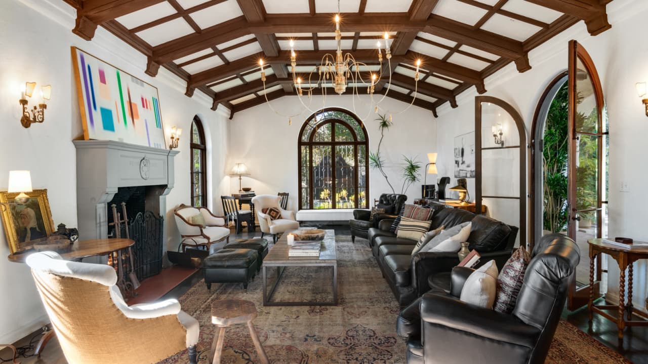 A large step-down living room has a vaulted ceiling with exposed wooden beams.