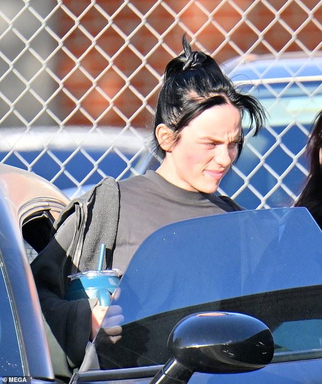 Relaxed: As she walked back to her car in Encino, alongside her trainer, on Wednesday, the Grammy winner cracked a smile as she toted a large blue reusable water bottle