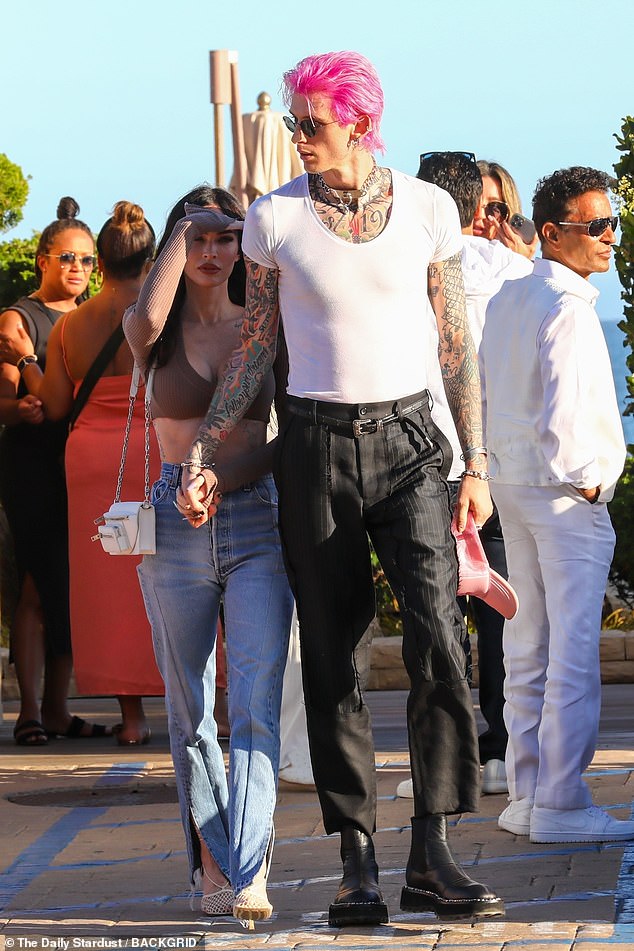 Lovebirds: MGK showed off his long frame in a white scoop neck tee tucked into striped black pants and chunky boots