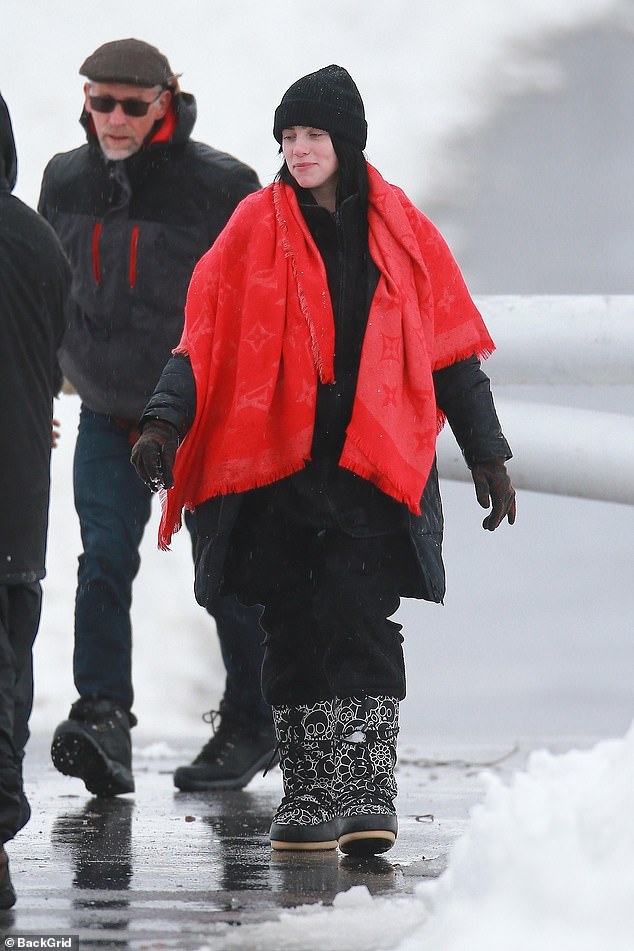 Pop of color: She wore a thick black jacket and draped a giant red scarf over her shoulders and wrapped it around herself like a blanket