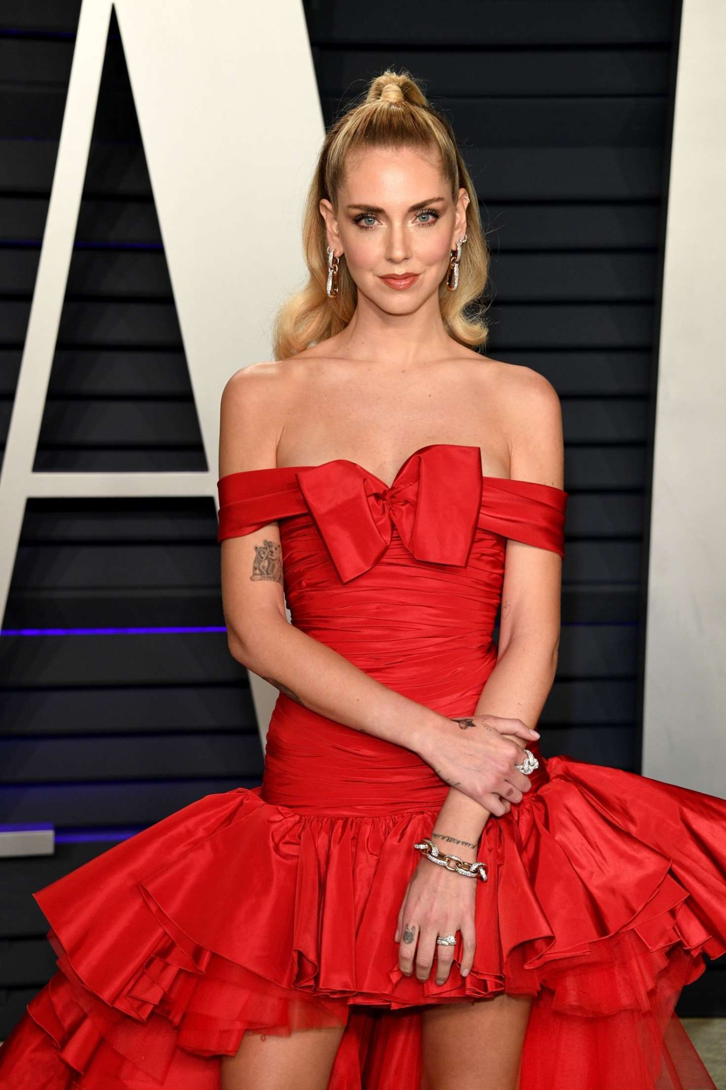 Chiara Ferragni, off-shoulder, red dress, black sandals, train length, low neck, voluminous, show off, ruffled, tulle detailing, red gown, floor scraping, bow neck, flare, long legs, ruched, drop waist, Layered