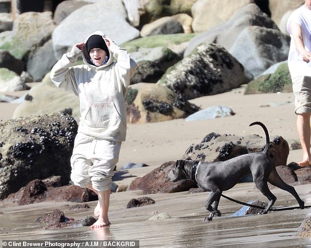 Low-key: The teen icon looked ultra comfortable yet chic in a matching cream colored sweatsuit, the pants of which she hiked up to run in the crashing surf