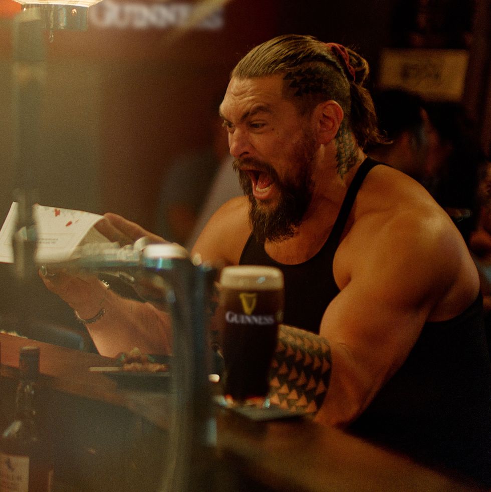 a man sitting at a table with a drink and a menu